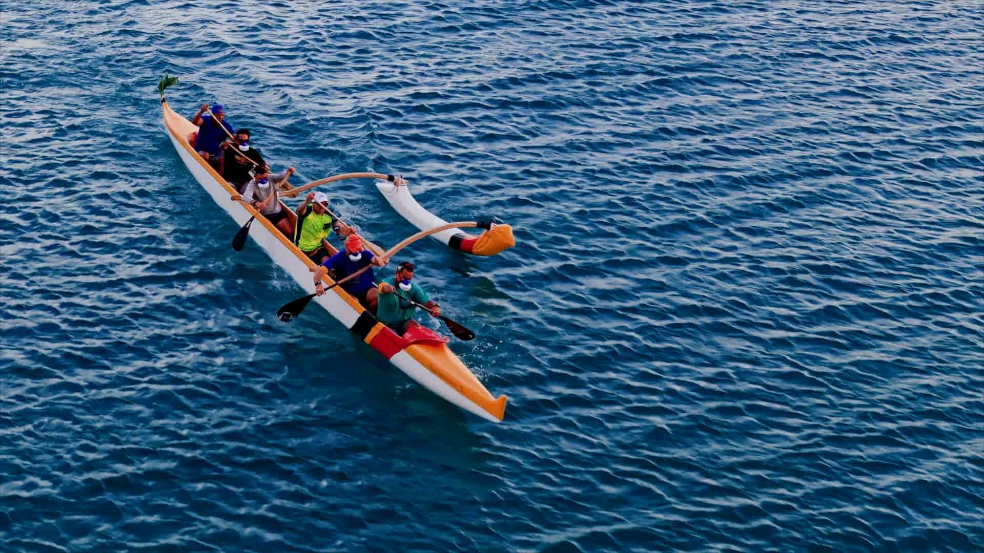 7 persons paddling a canoe with outrigger