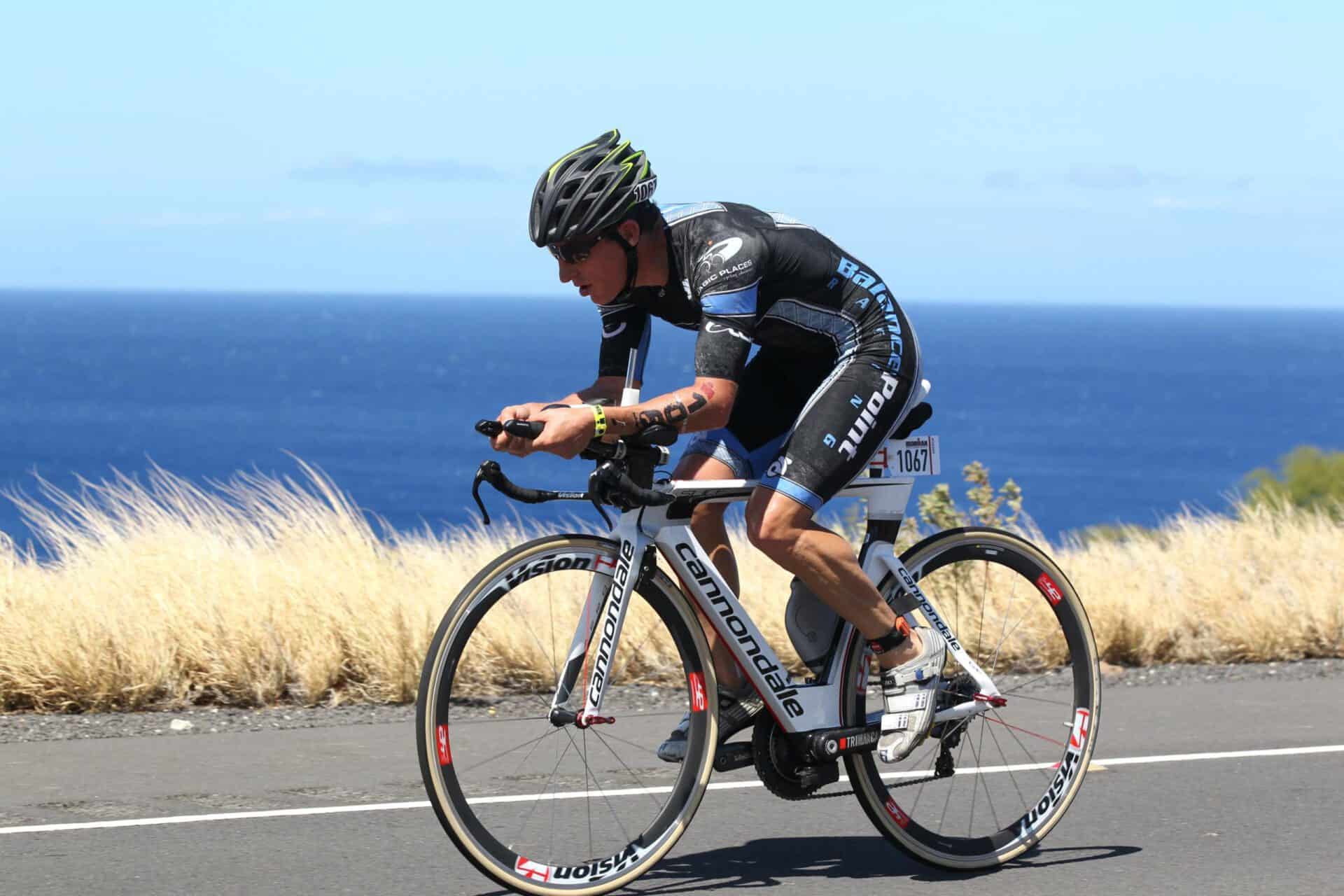 Male athlete is seen road biking along a scenic highway.