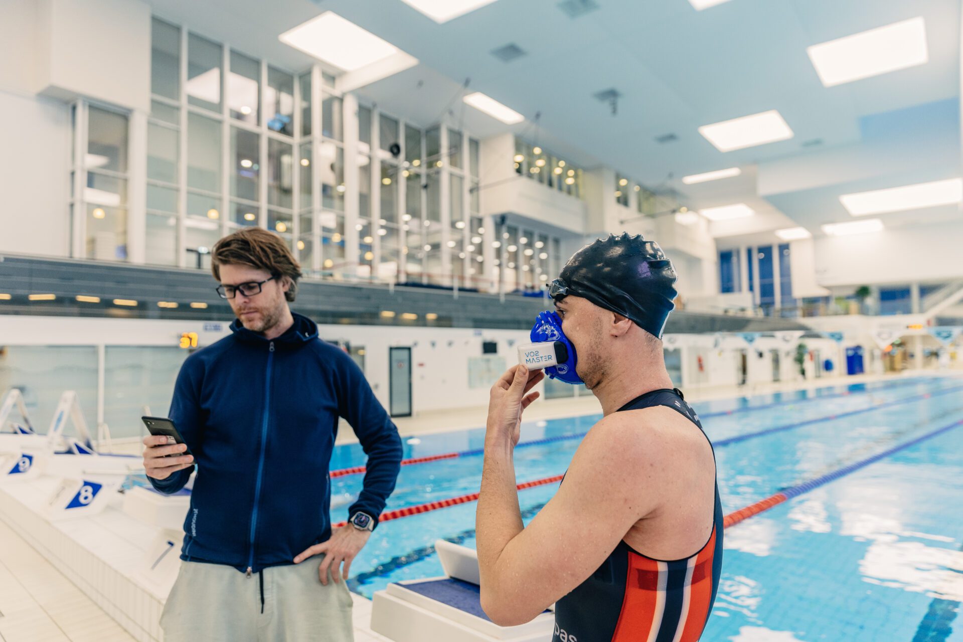 triathlete gustav iden with coach olav aleksander bu standing outside of the pool testing vo2max after a training session with the vo2 master portable metabolic analyzer 