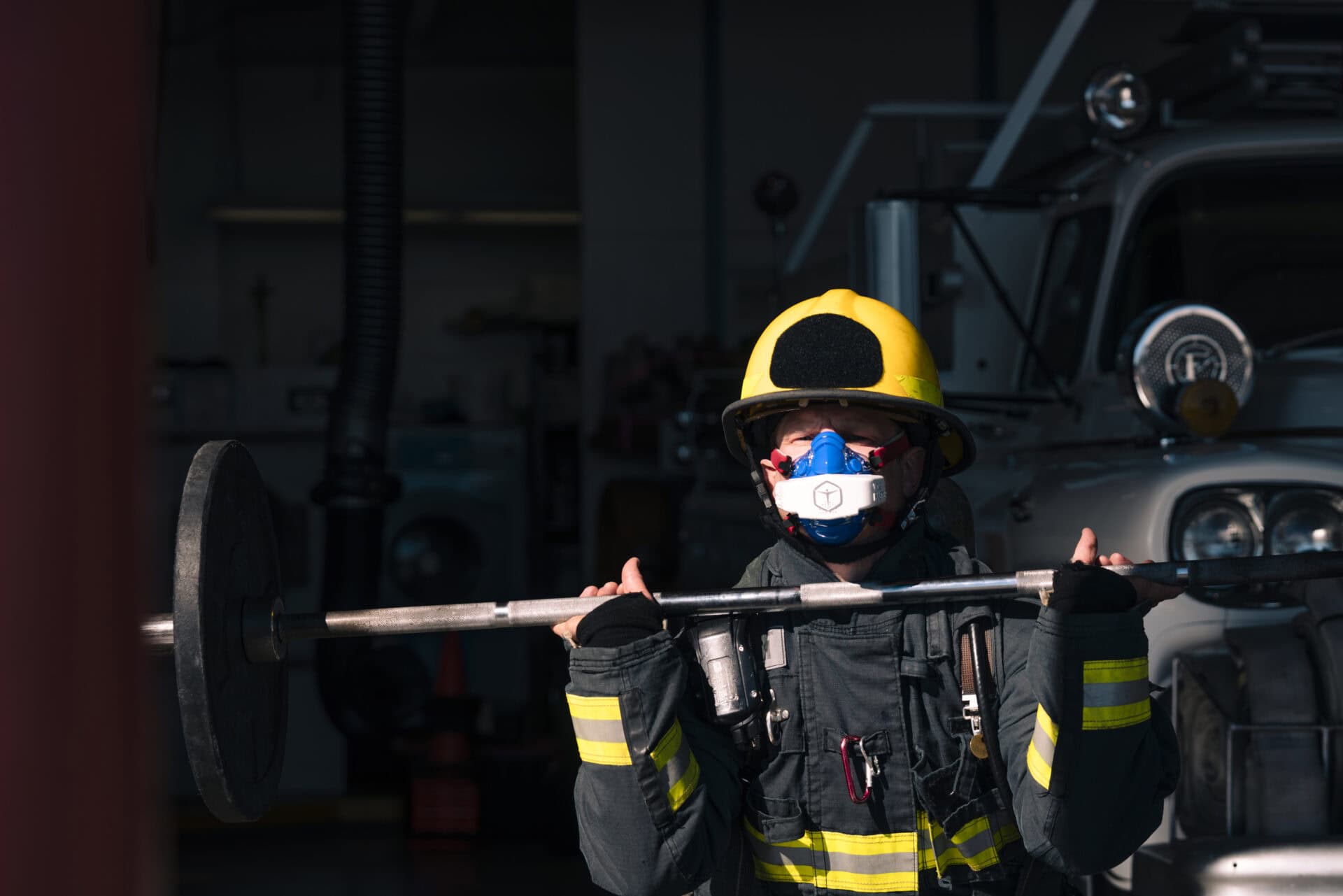 a firefighter lifting a barbell in full gear while using a vo2 master portable metabolic analyzer