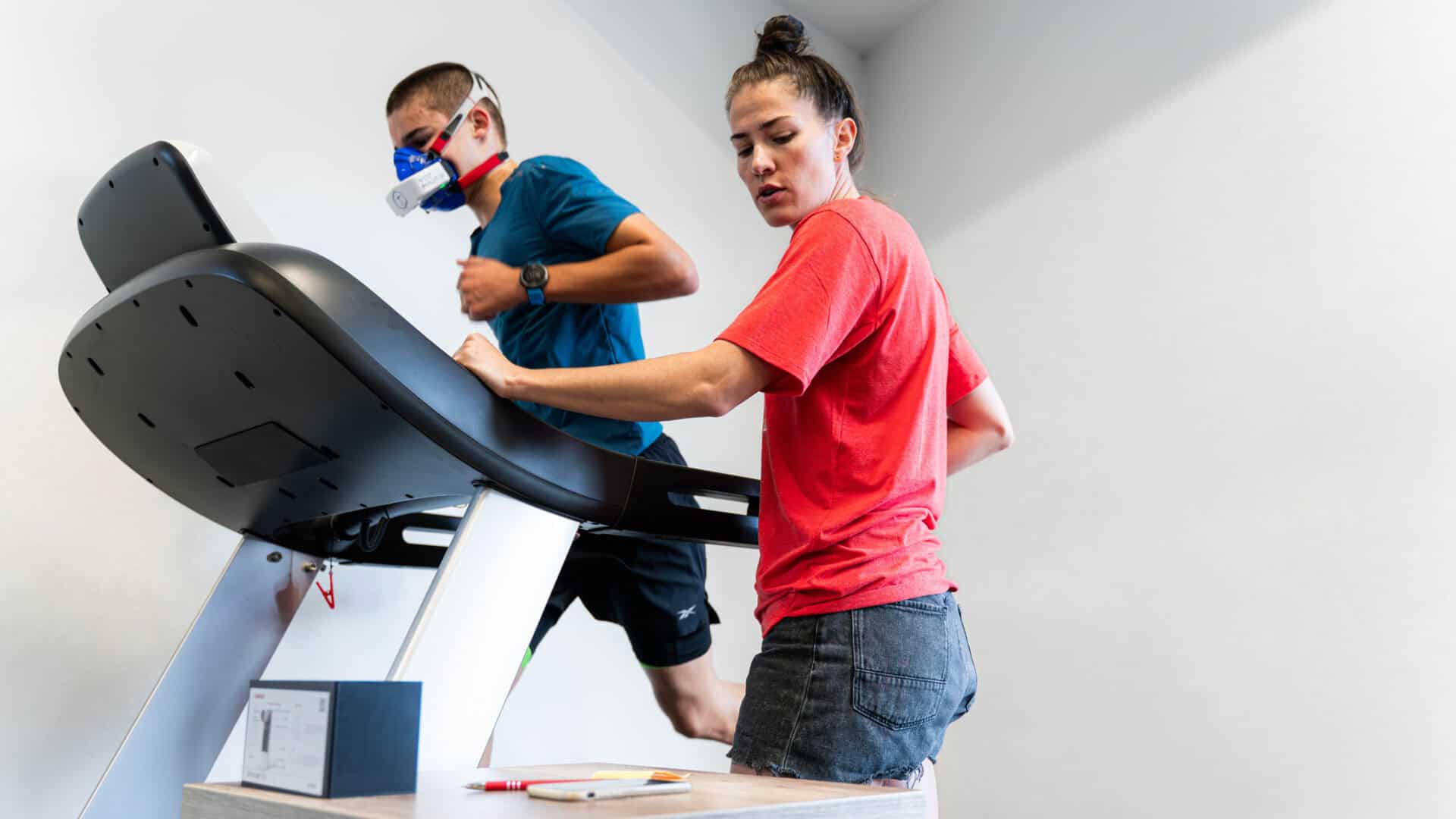 Athlete running on a treadmill as a coach monitors performance during a metabolic test