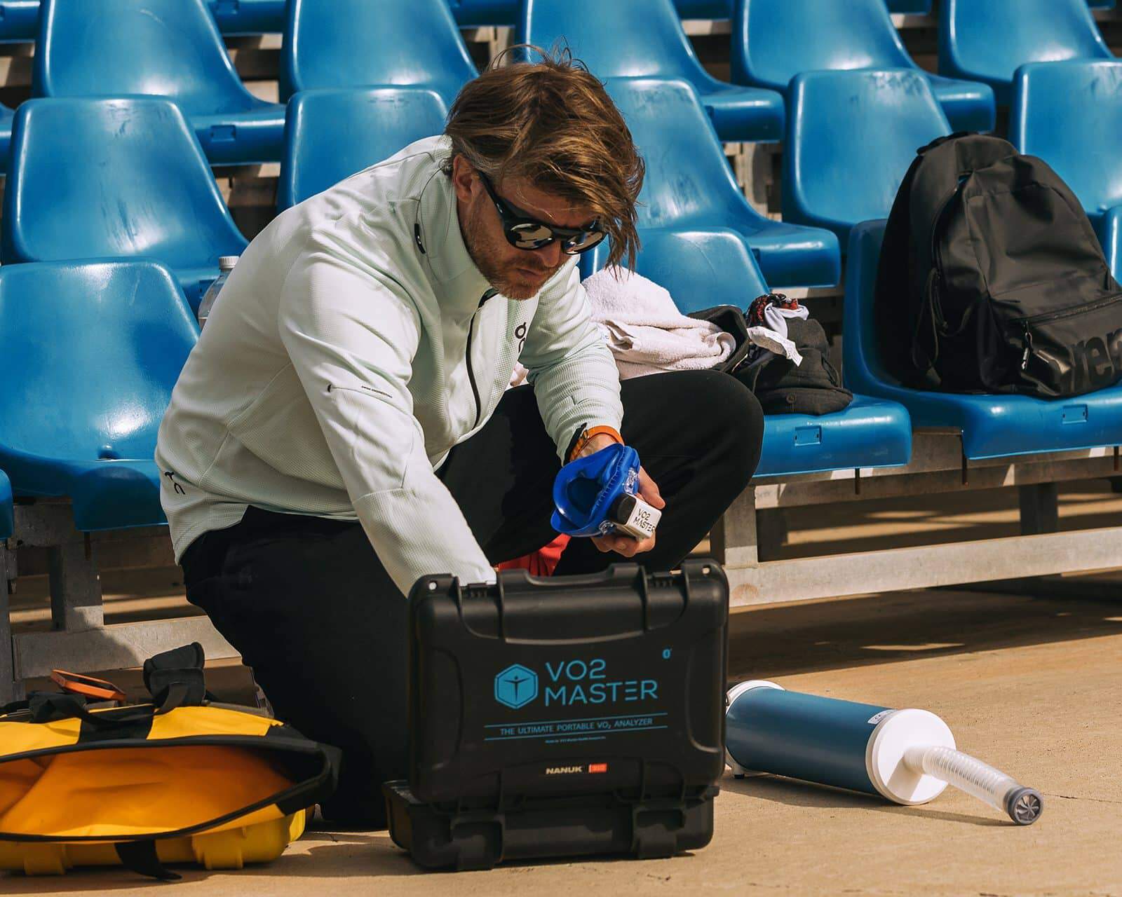 Olav Aleksander opening the VO2 Master kit in a stadium with blue chairs