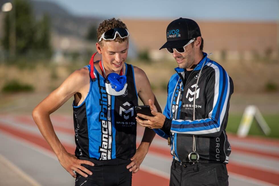 Trainer showing an athlete performance results on an iPhone while the VO2 analyzer hangs on his neck