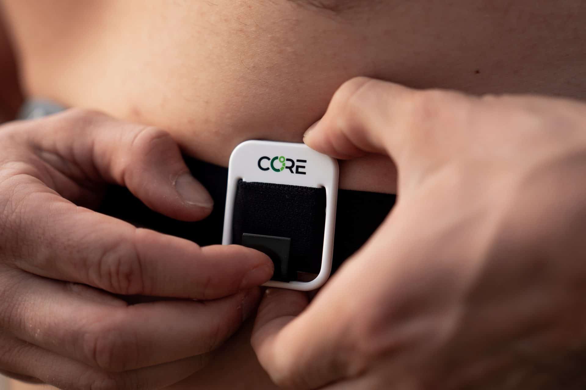 an athlete fastening a core body temperature monitor around his chest while training
