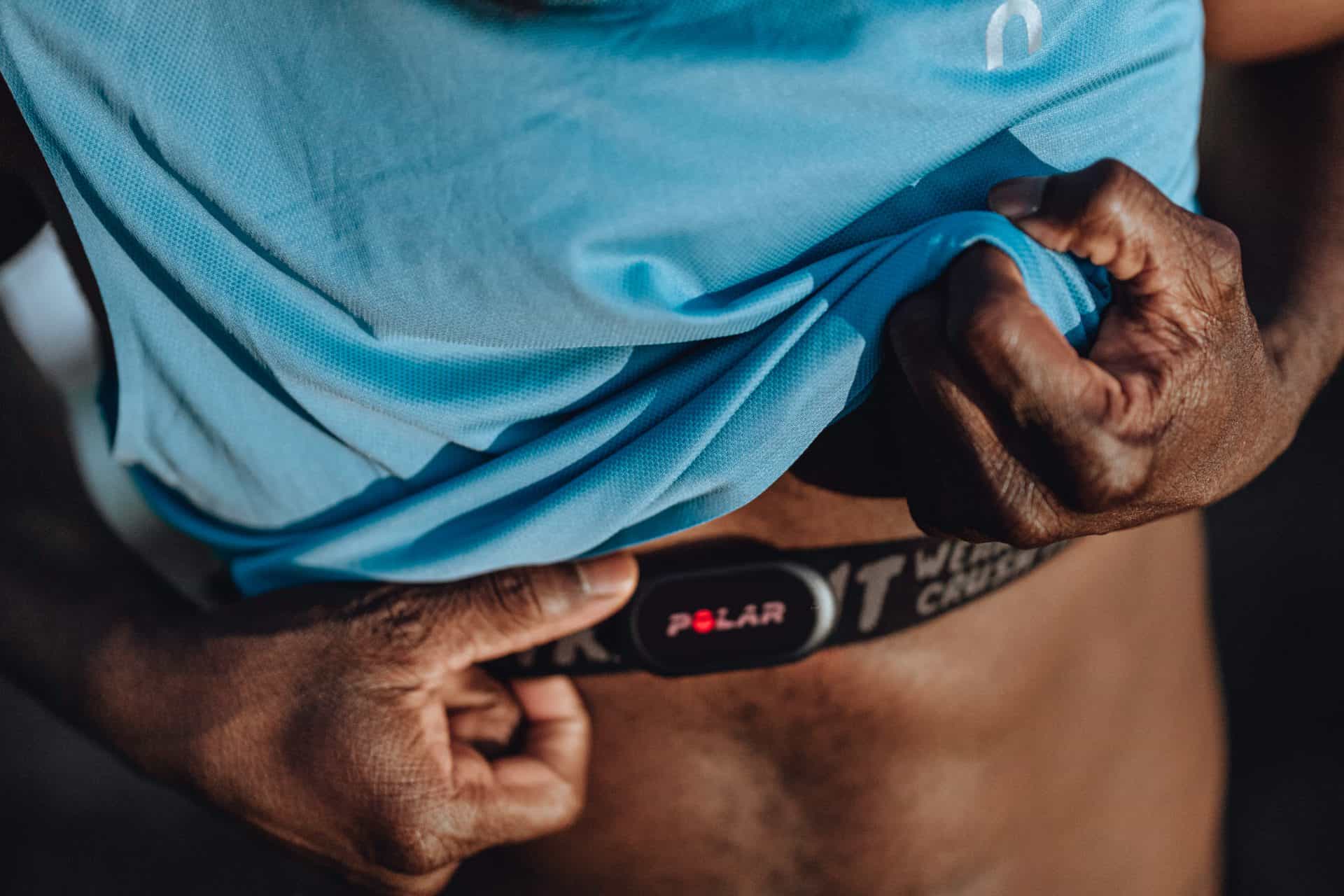 an athlete in a blue shirt using a polar heart rate monitor