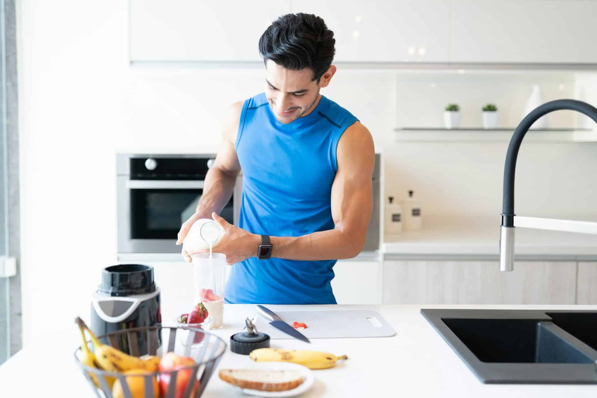 an athlete after a workout making a healthy smoothie in his kitchen